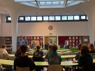 Powiększ obraz: Uczestnicy lekcji siędzący przy stolikach