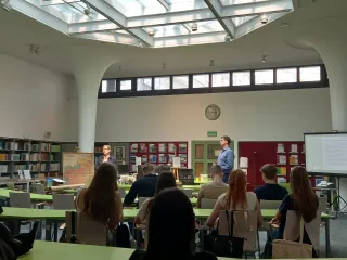 Powiększ obraz: Uczestnicy lekcji siędzący przy stolikach