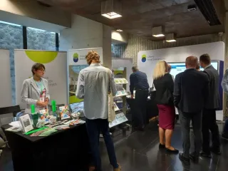 Powiększ obraz: Grupa osób obok stoisk informacyjnych