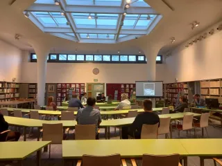 Powiększ obraz: Uczestnicy spotkania siędzący przy stolikach w czytelni